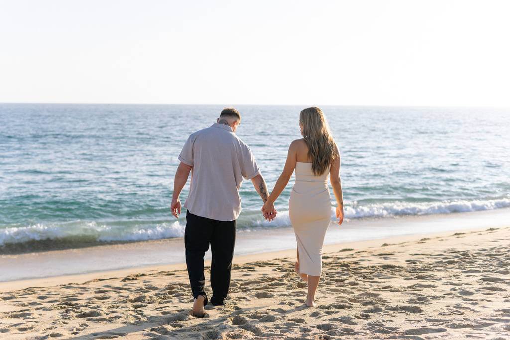hand in hand beach walk engagement pose